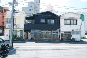 a black building on the corner of a street at Atelier & Hostel Nagaisa-Ura in Atami