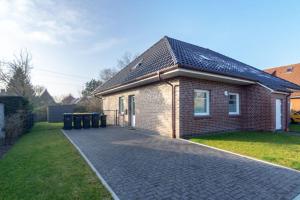 une maison en briques avec des poubelles devant dans l'établissement Ferienhaus-Lucky-bis-6-Personen-mit-Garten-und-Haustier, à Norddeich