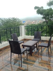 three chairs and a table on a balcony at Casa Mount View villa wd pvt pool in Lonavala