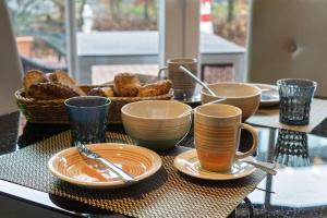einen Tisch mit Teller und Tassen und einen Korb Brot in der Unterkunft Ferienwohnung Ambiente in Norddeich + 20 Fotos