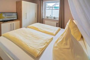 1 Schlafzimmer mit 2 Betten und gelber Bettwäsche in der Unterkunft Ferienwohnung Ambiente in Norddeich