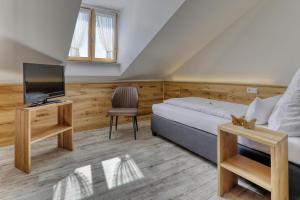 シュピーゲラウにあるHotel Waldfrieden "Das kleine Hotel"のベッド、テレビ、椅子が備わる客室です。