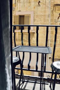 a black bench sitting on a balcony with two chairs at The Mike Hotel by CX Collection in Cospicua