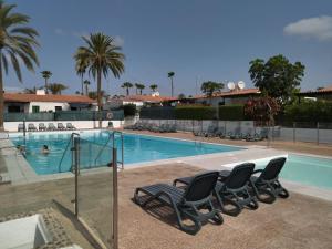 a swimming pool with chairs next to a resort at Tartanas 144 playa del inglés, jumbo in Playa del Ingles