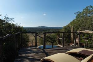 una terraza de madera con bañera de hidromasaje en una colina en Pumba Private Game Reserve en Grahamstown