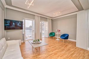 a living room with a white couch and two chairs at THE YDRA VIEW APARTMENTS in Hydra