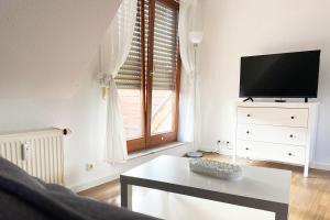 sala de estar con TV, mesa y ventana en Schönes 1 Zimmer Apartment mit Dachterrasse, en Glauchau