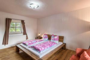 um quarto com uma cama com lençóis cor-de-rosa e uma janela em Zuhaus am See em Gstadt am Chiemsee