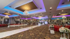 un salón de banquetes con mesas rojas y blancas y lámparas de araña en Classie Hotel, en Palembang