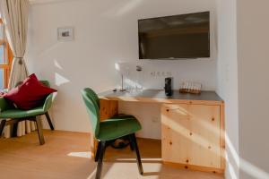 Habitación con escritorio y TV en la pared. en Polreich Bed&Breakfast, en Hallstatt