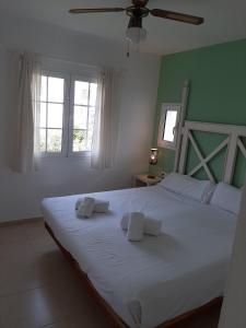 a bedroom with a large white bed with green walls at APARTAMENTOS SON BOU Z5 in Son Bou