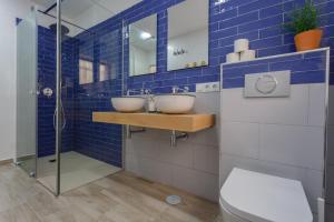 W wyłożonej niebieskimi kafelkami łazience znajdują się 2 umywalki i prysznic. w obiekcie TACITA Family Home by Cadiz4Rentals w Kadyksie