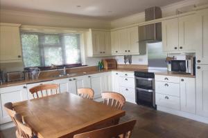 a kitchen with a wooden table and wooden chairs at Ashwood Holiday Cottage. in Ashford