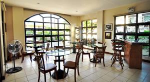 un ristorante con tavoli, sedie e finestre di El Haciendero Private Hotel a Città di Iloilo