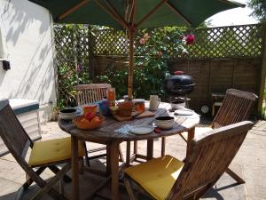 una mesa de madera con sillas y una sombrilla en Robin Hill Cottage, en Amesbury