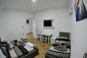 a bedroom with two beds and a desk and a television at Hotel Reci in Peshkopi
