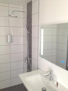 a bathroom with a shower with a sink and a mirror at Cit'Hotel Le Mirage in Istres