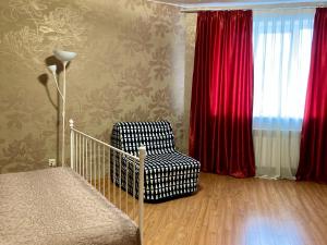 スルグトにあるApartment on Voshod 21のベッドルーム1室(椅子付)、赤いカーテン付きの窓が備わります。
