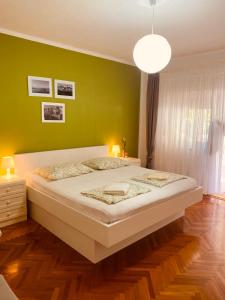 a bedroom with a large bed with a green wall at Villa Chiara in Vodice