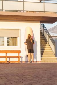 a person standing next to a wall with a surfboard at Hospedium Hostel República Surf House in Ericeira