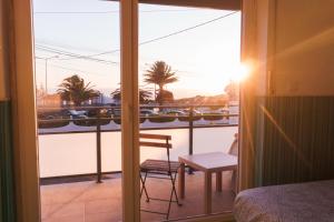 a room with a view of a balcony with a bed and a chair at Hospedium Hostel República Surf House in Ericeira