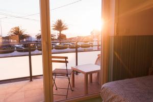 a bedroom with a balcony with a bed and a chair at Hospedium Hostel República Surf House in Ericeira