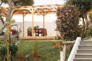 a wooden pergola in a garden with a table and bench at Hospedium Hostel República Surf House in Ericeira
