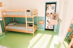 a room with two bunk beds and a green floor at Hospedium Hostel República Surf House in Ericeira