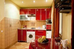 a kitchen with red cabinets and a bowl of fruit on a table at Hotel Nataly on Srednemoskovskaya 7 in Voronezh