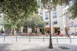 eine Straße mit Tischen und Stühlen vor einem Gebäude in der Unterkunft GemBnB Luxury Apartments - Residence Thorigny Paris - Marais in Paris
