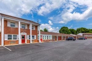 un edificio de ladrillo con puertas rojas y aparcamiento en Econo Lodge Woodstock - Shenandoah Valley I-81, en Woodstock