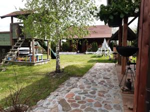 a garden with a tree and a stone walkway at Domek w Kwiatach in Mrągowo