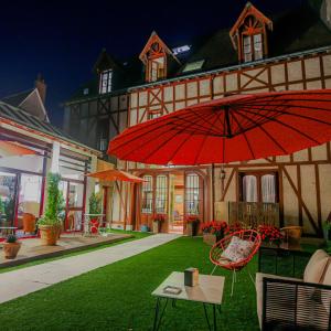 une maison avec un parasol rouge, une table et des chaises dans l'établissement Hotel Spa - Au Charme Rabelaisien, à Amboise