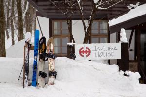 un montón de esquís en la nieve delante de una casa en Hakuba House, en Hakuba