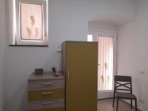 Pokój z zieloną szafką, krzesłem i oknem w obiekcie Ortigia spartan house 3 w Syrakuzach
