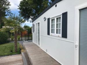 a small white house with a wooden deck at RBR 1211 - Beach Resort Kamperland in Kamperland