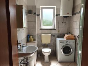 a bathroom with a toilet sink and a washing machine at Apartments Topalović in Kostrena