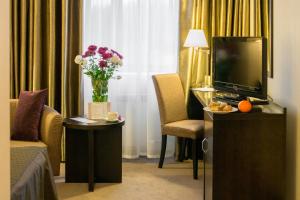 a hotel room with a television and a vase of flowers at RiverSide- Restaurant, Hotel, Beach in Chernihiv