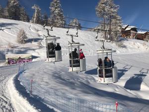 a group of people riding on a ski lift in the snow at Appartements duplex dans chalet - Pléiades -, skis aux pieds avec clefs à disposition via agence -nous louons l'un et-ou l'autre des deux appartements de notre chalet quasiment identiques in Risoul