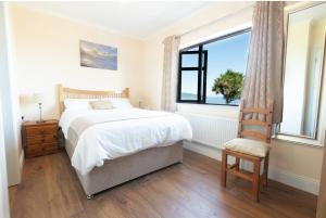 a bedroom with a bed and a chair and a window at Beenoskee Bed and Breakfast in Castlegregory