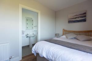 a bedroom with a bed and a bathroom with a sink at Beenoskee Bed and Breakfast in Castlegregory