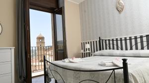 Un dormitorio con una cama y un balcón con una torre de reloj. en B&b La Margherita en Pietrapertosa