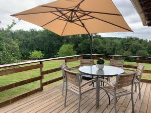 a table and chairs on a deck with an umbrella at La caseta Domaine du CANTEAU YF in Panjas