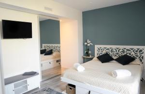a bedroom with a white bed and a mirror at la casa di Gaia in Taormina