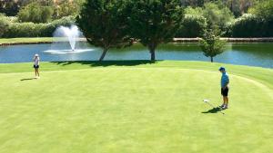 2 personnes jouant au golf sur un parcours avec une fontaine dans l'établissement MI CAPRICHO 4B BEACHFRONT - Apartment with sea view - Costa del Sol -, à La Cala de Mijas