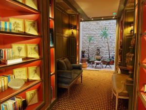 a living room with bookshelves and a chair and a window at Hôtel du Vieux Marais in Paris