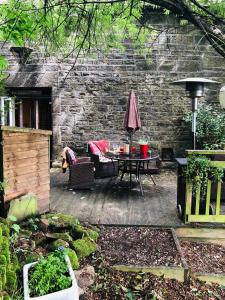 a patio with a table and chairs and a stone wall at Lane House Farm in Todmorden
