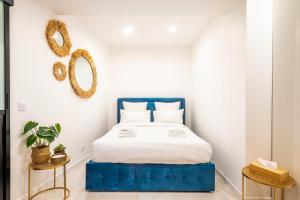 ein Schlafzimmer mit einem blauen Bett mit weißer Bettwäsche und Spiegeln in der Unterkunft GemBnB Luxury Apartments - Residence Thorigny Paris - Marais in Paris
