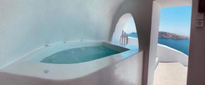 biała łazienka z jacuzzi z oceanem w obiekcie Lioyerma Cave Villa With Private Outdoor Hot Tub w mieście Oia
