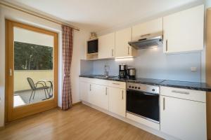 a kitchen with white cabinets and a stove top oven at Ferienhaus Maria Edelweiss in Pfelders +13 photos